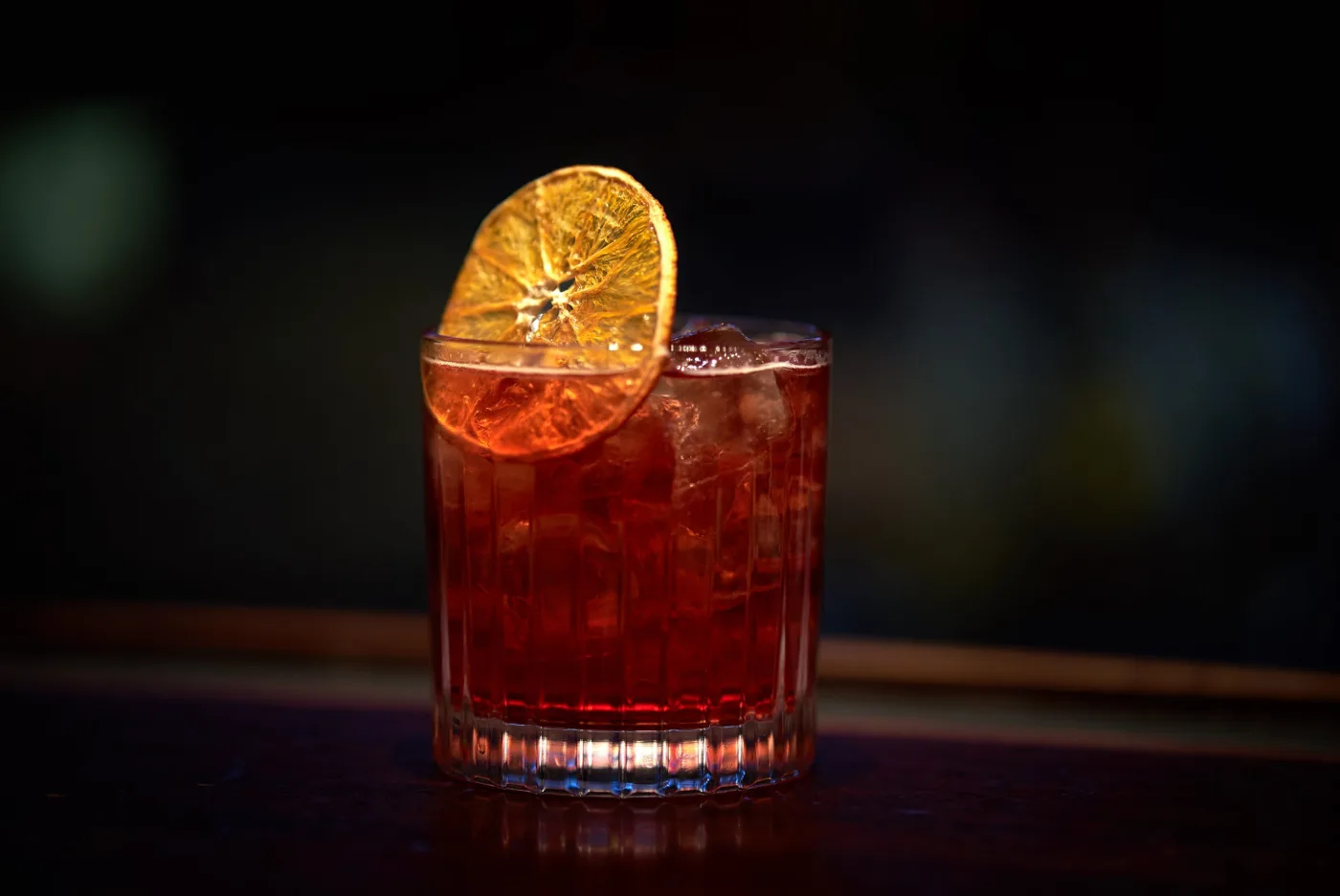 Abissinia: twist sull'Americano rosso scuro in tumbler basso con ghiaccio e rondella di arancia essiccata