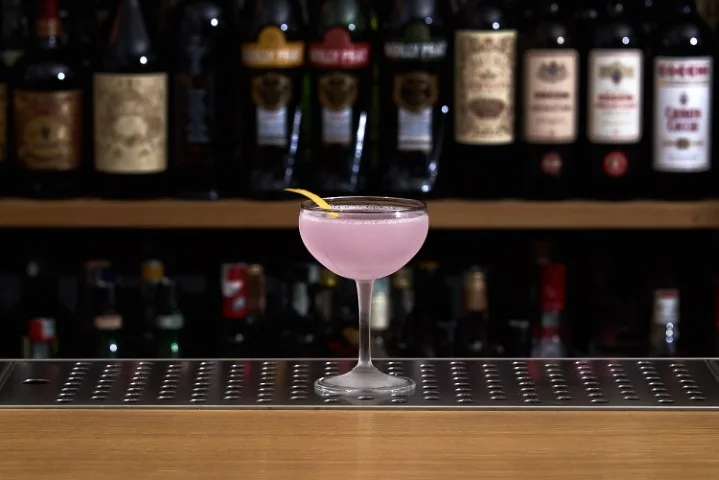 Aviation color lilla in coppa con twist di limone su banco bar
