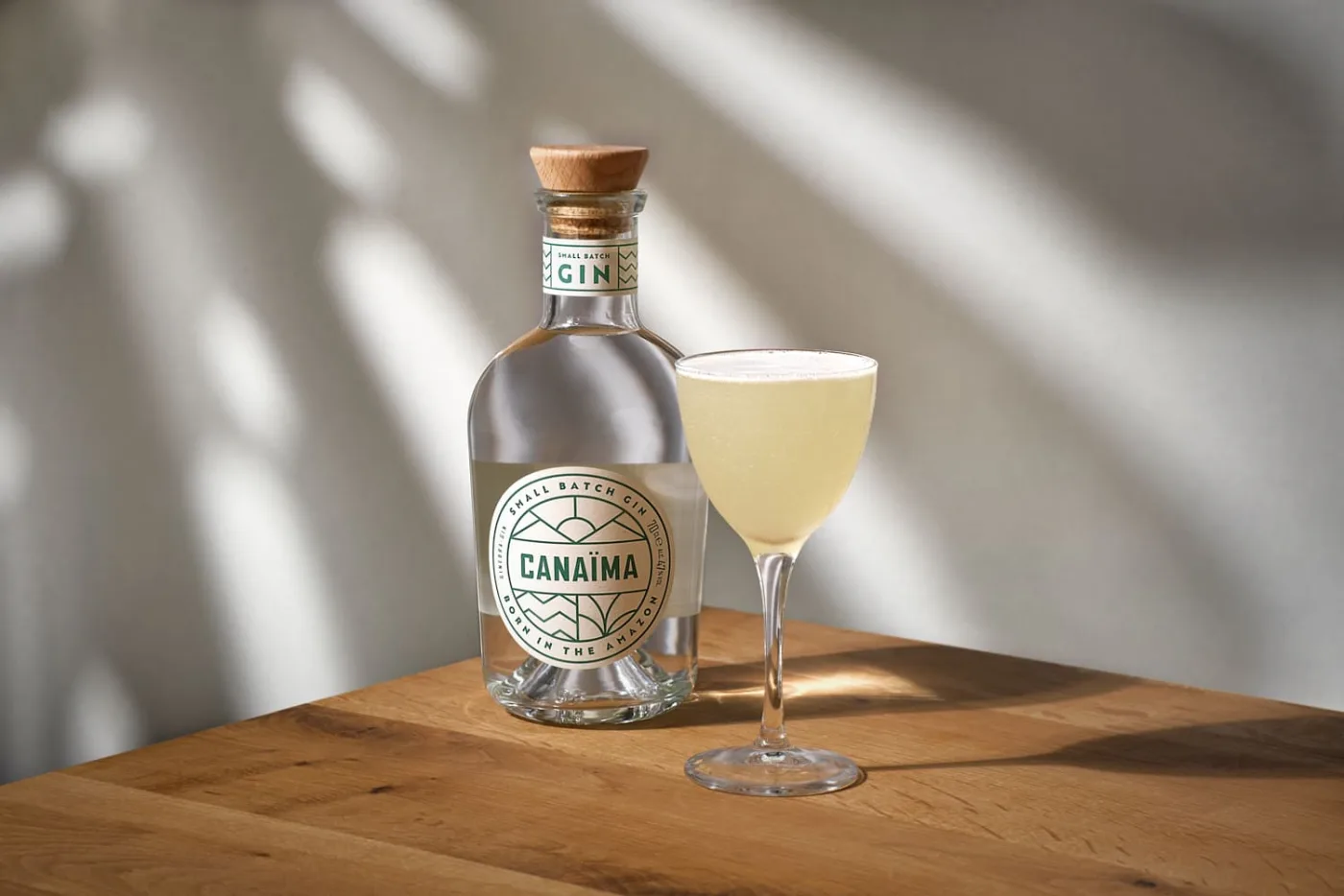 Bee's Knees in coppetta accanto a una bottiglia di gin Canaïma su tavolo di legno
