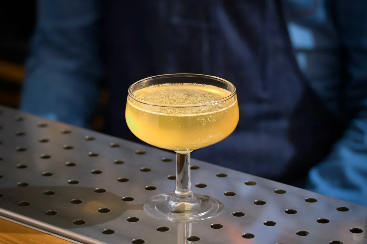 Il Between the Sheets, dal colore giallo dorato, servito in una piccola coppetta vintage su un banco bar