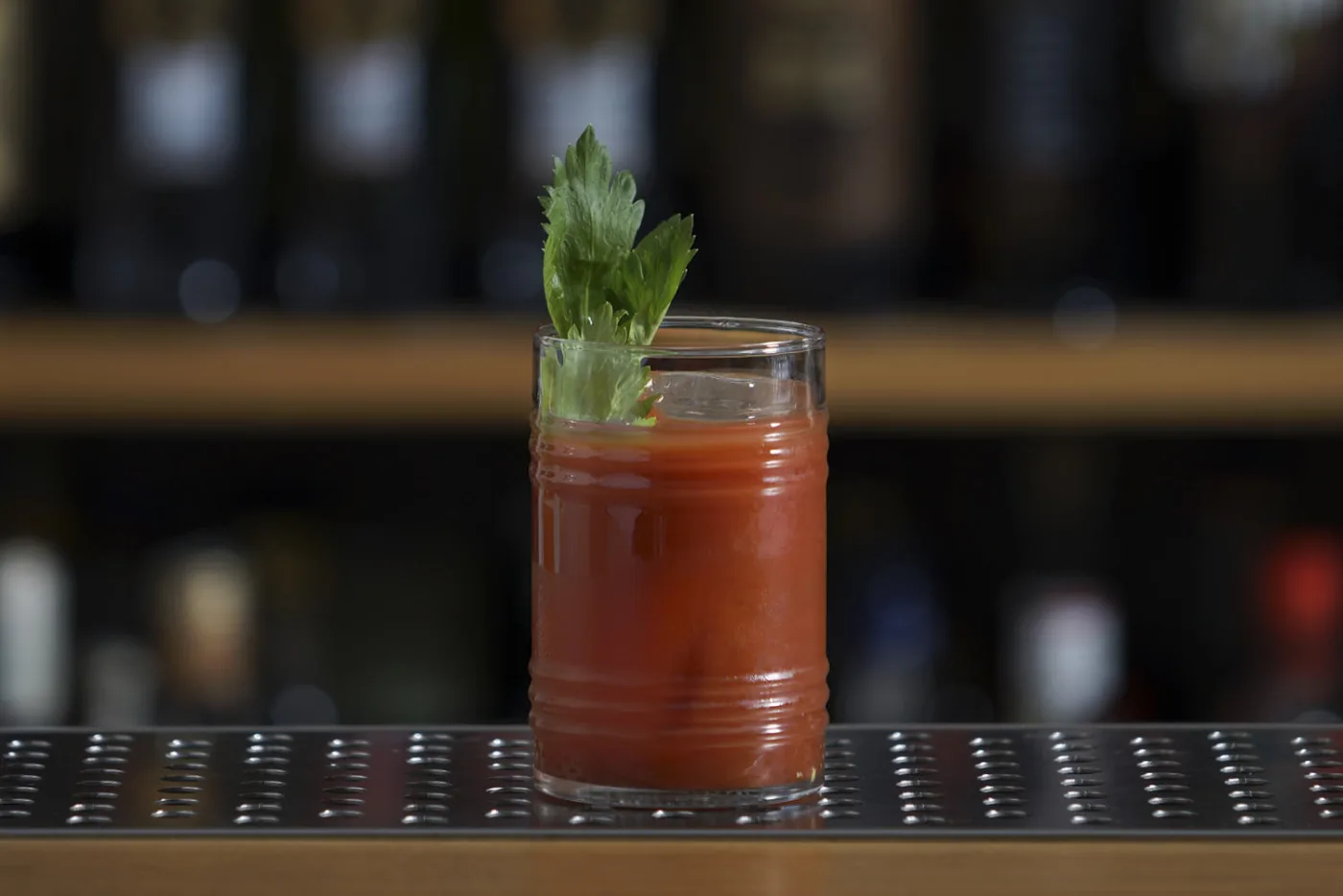 Bloody Mary in tumbler alto con ciuffo di sedano su banco bar
