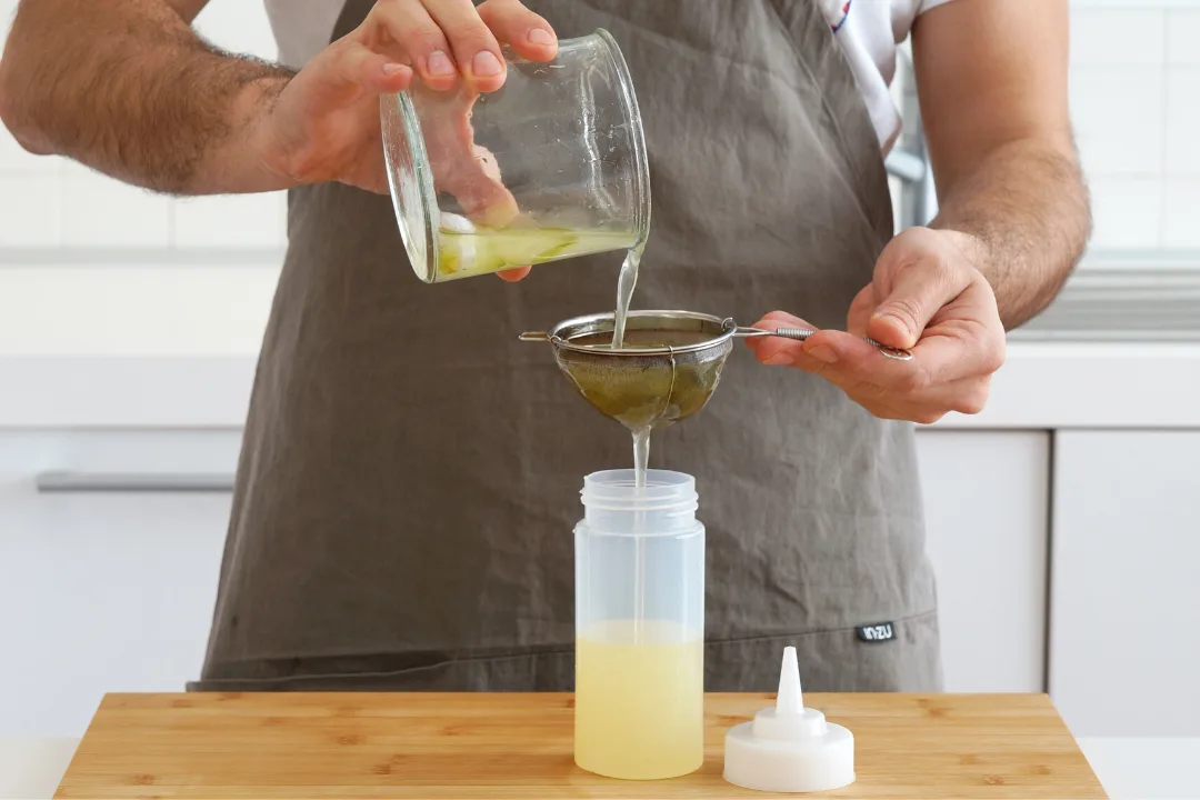 Il lime cordial filtrato con un colino dentro uno squeezer