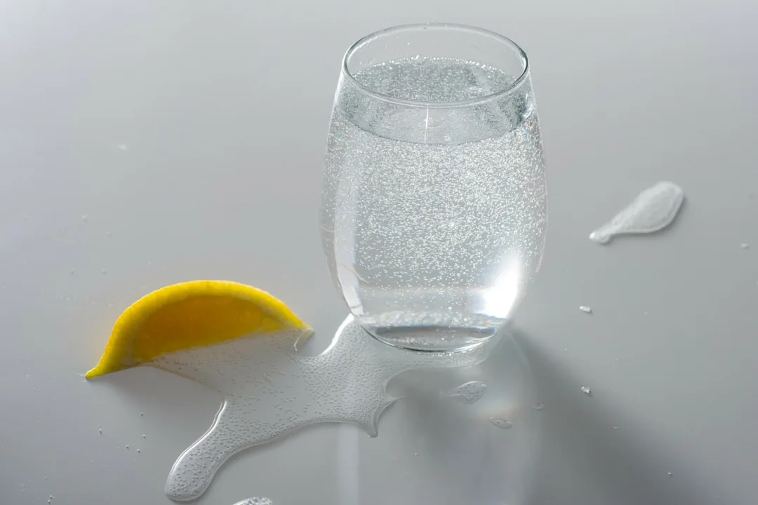 Bicchiere con bevanda effervescente e bollicine che risalgono verso la superficie