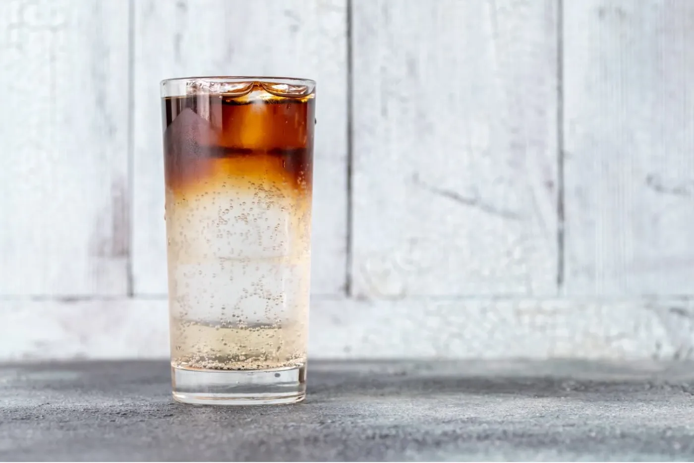 Il Dark 'n Stormy in un tumbler alto con ghiaccio, con lo strato scuro di rum stratificato sopra la ginger beer