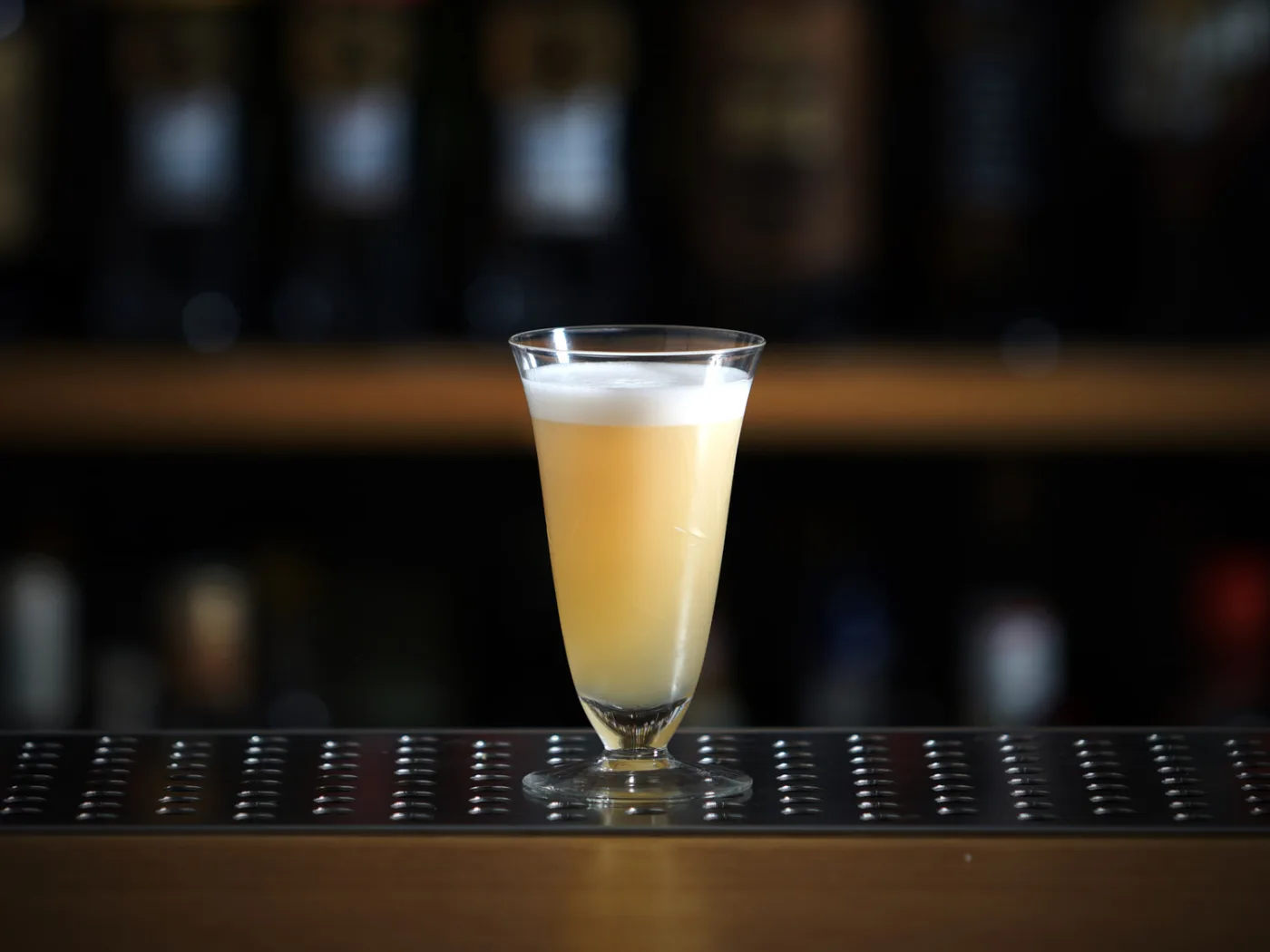 Delicious Sour giallo pallido con schiuma compatta in calice svasato su banco bar