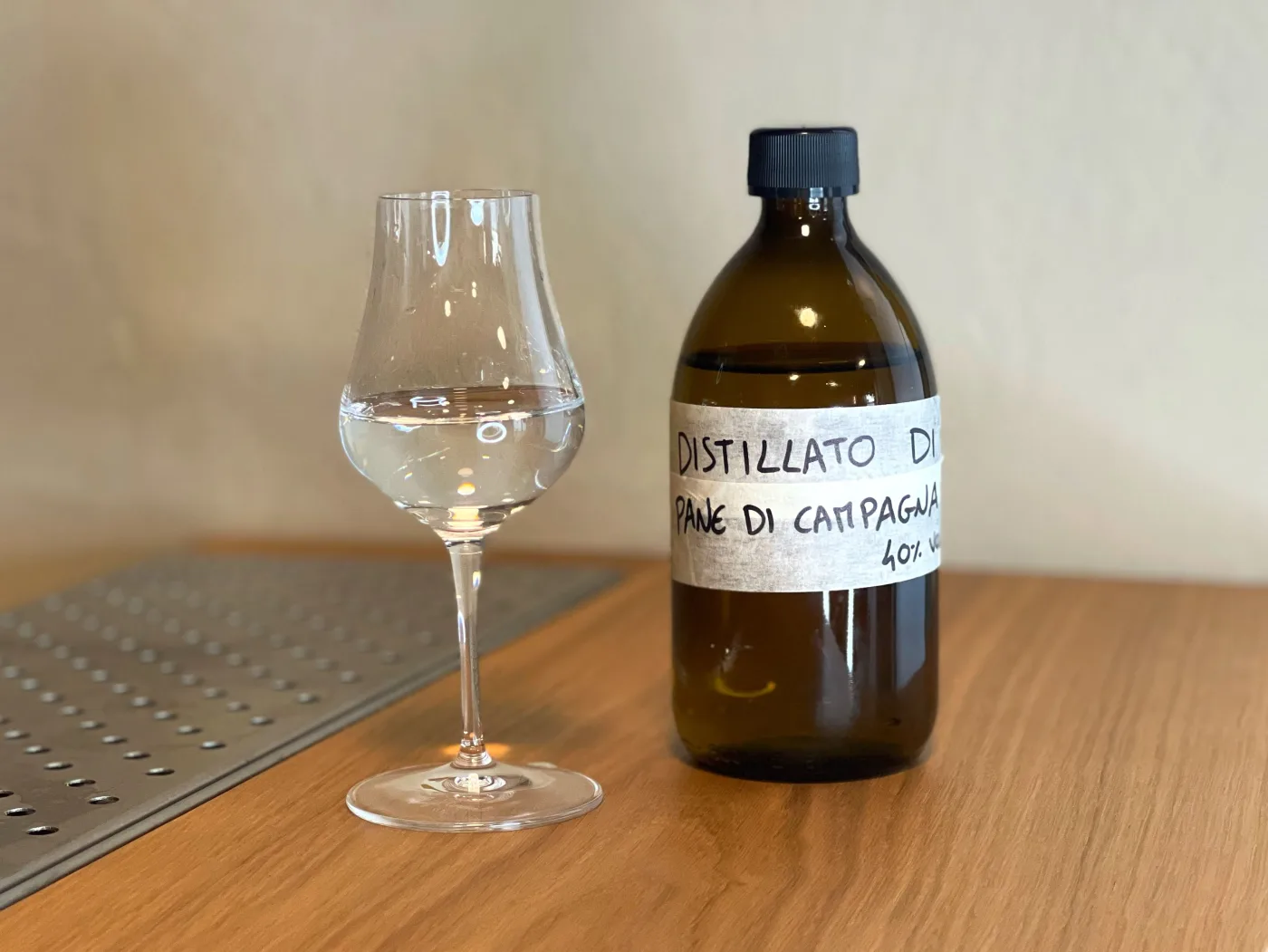 Bicchiere da degustazione e bottiglia ambrata con etichetta scritta a mano Distillato di pane di campagna 40% vol