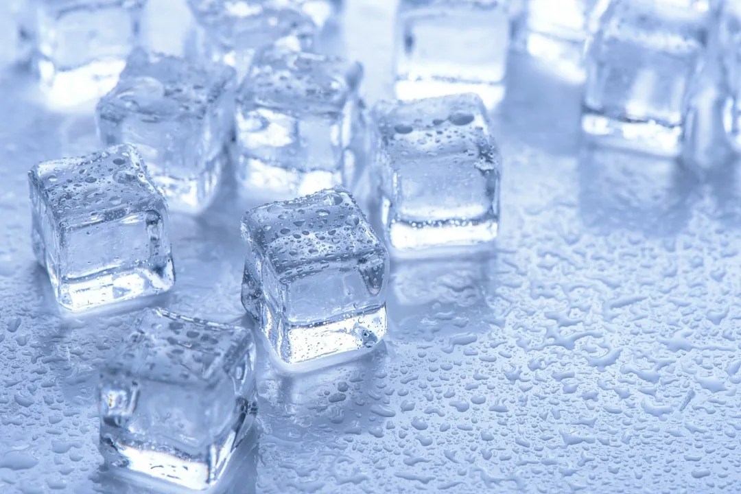 Cubetti di ghiaccio trasparenti appoggiati su una superficie coperta di gocce d’acqua