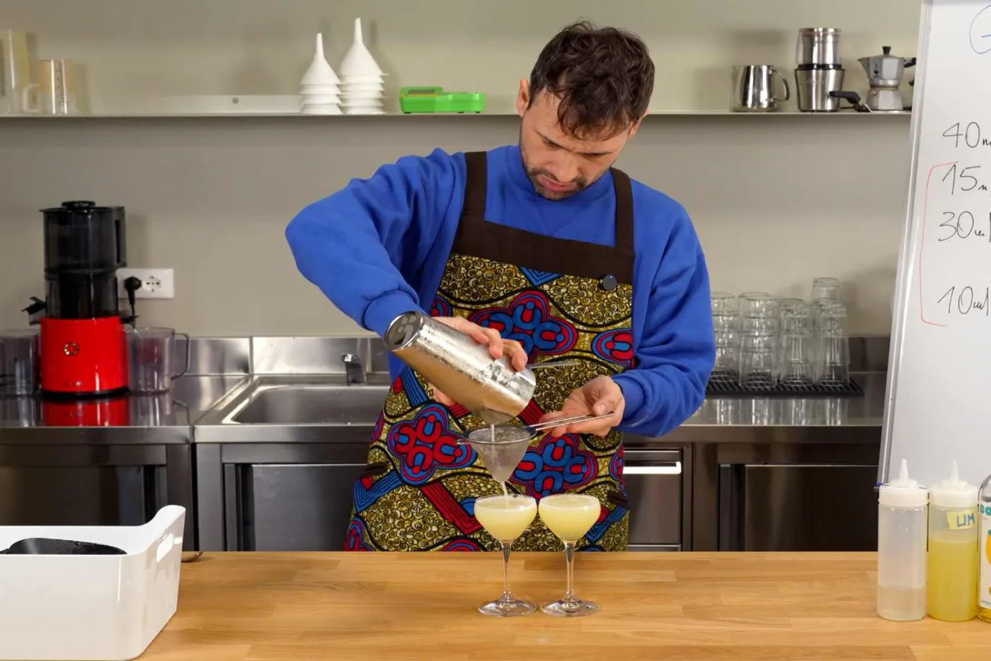 Bartender filtra con double strain il Gimlet senza Lime Cordial in due coppette da cocktail