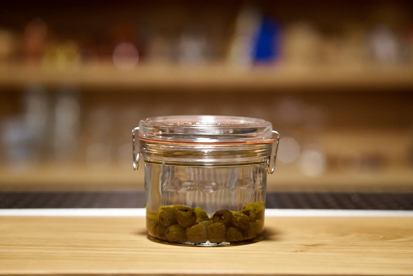 Barattolo ermetico con olive in infusione nel gin sul banco del bar