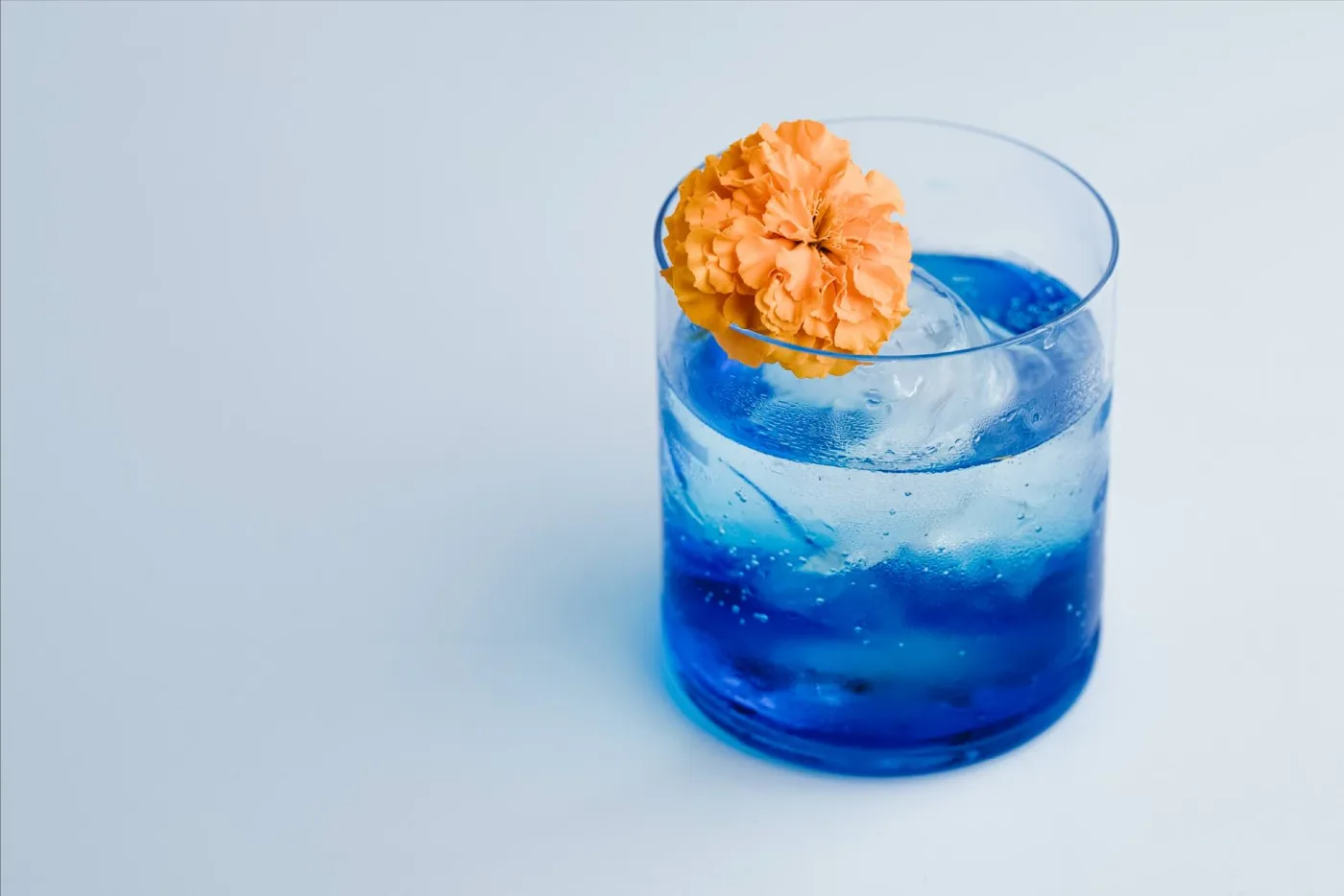 Cocktail blu con guarnizione di fiore giallo, esempio di colori complementari