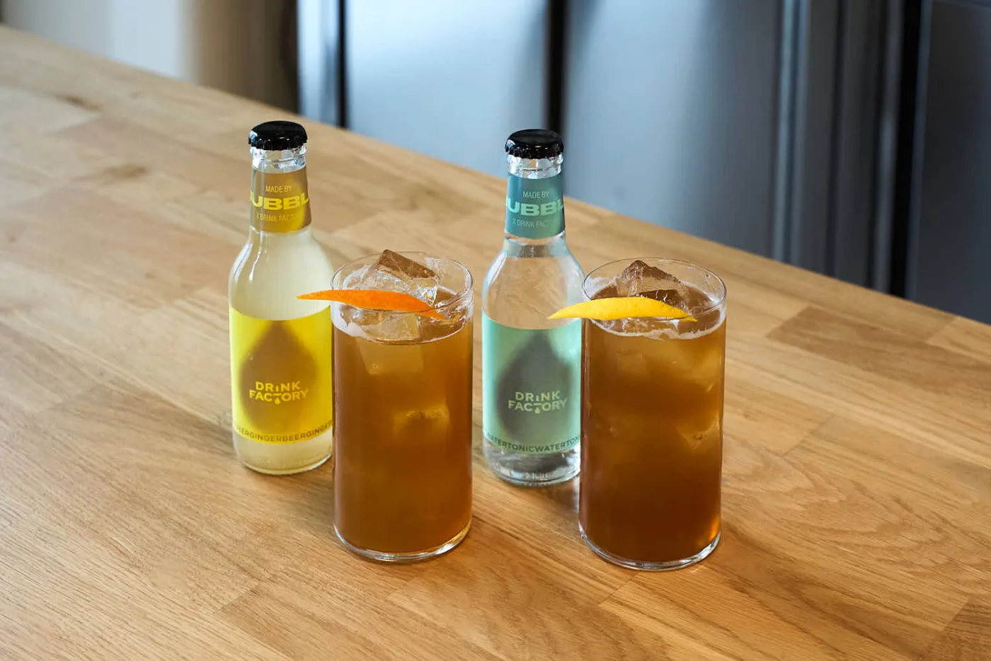 Due cocktail analcolici con Indian Chai Coffee Cordial e twist di agrumi, accanto a bottigliette di ginger beer e acqua tonica artigianali