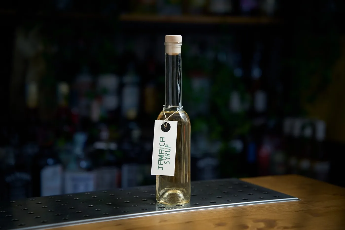 Bottiglia di Jamaica Syrup con etichetta artigianale sul banco del bar