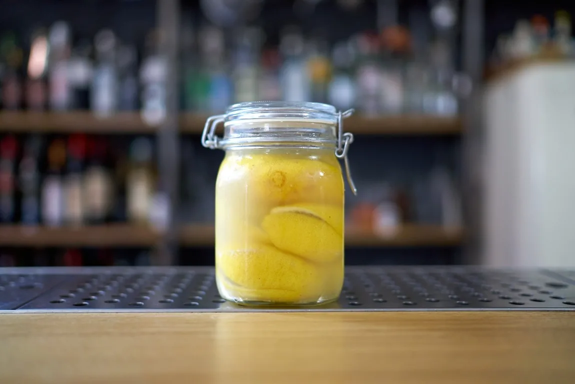 Barattolo a chiusura ermetica pieno di limoni marocchini sotto sale sul bancone di un bar