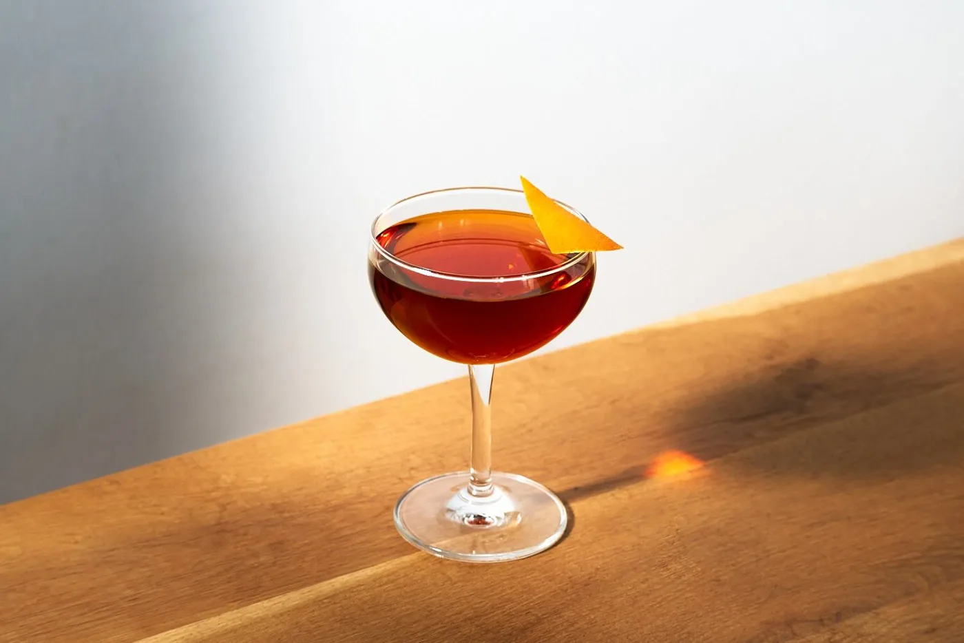 Il Manhattan servito in una coppetta da cocktail, con un twist di arancia incastrato sul bordo del bicchiere