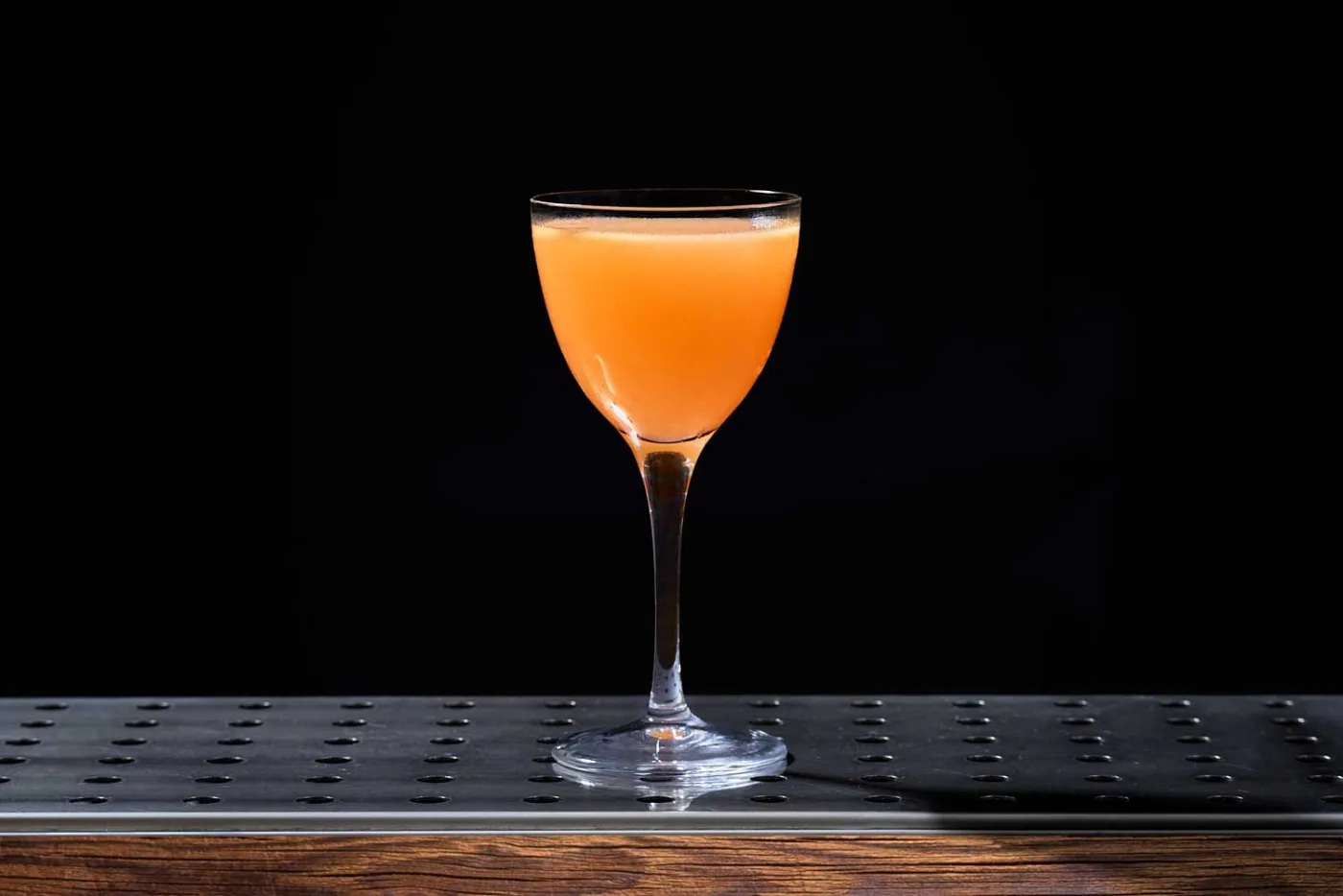Il Monkey Gland, dal colore arancio, servito in una coppetta Nick & Nora su un banco bar scuro