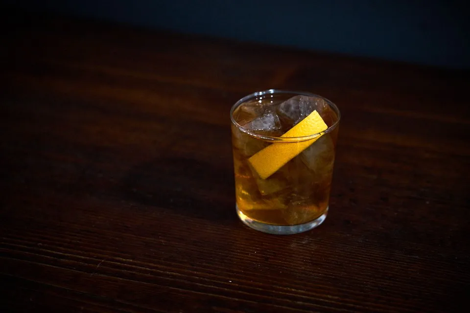 Old Fashioned servito in tumbler basso con ghiaccio e scorza di arancia