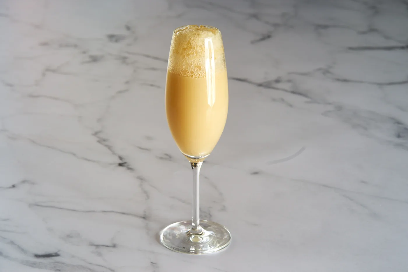 Panettone Bellini: flute con drink color crema e cappello di schiuma su piano di marmo