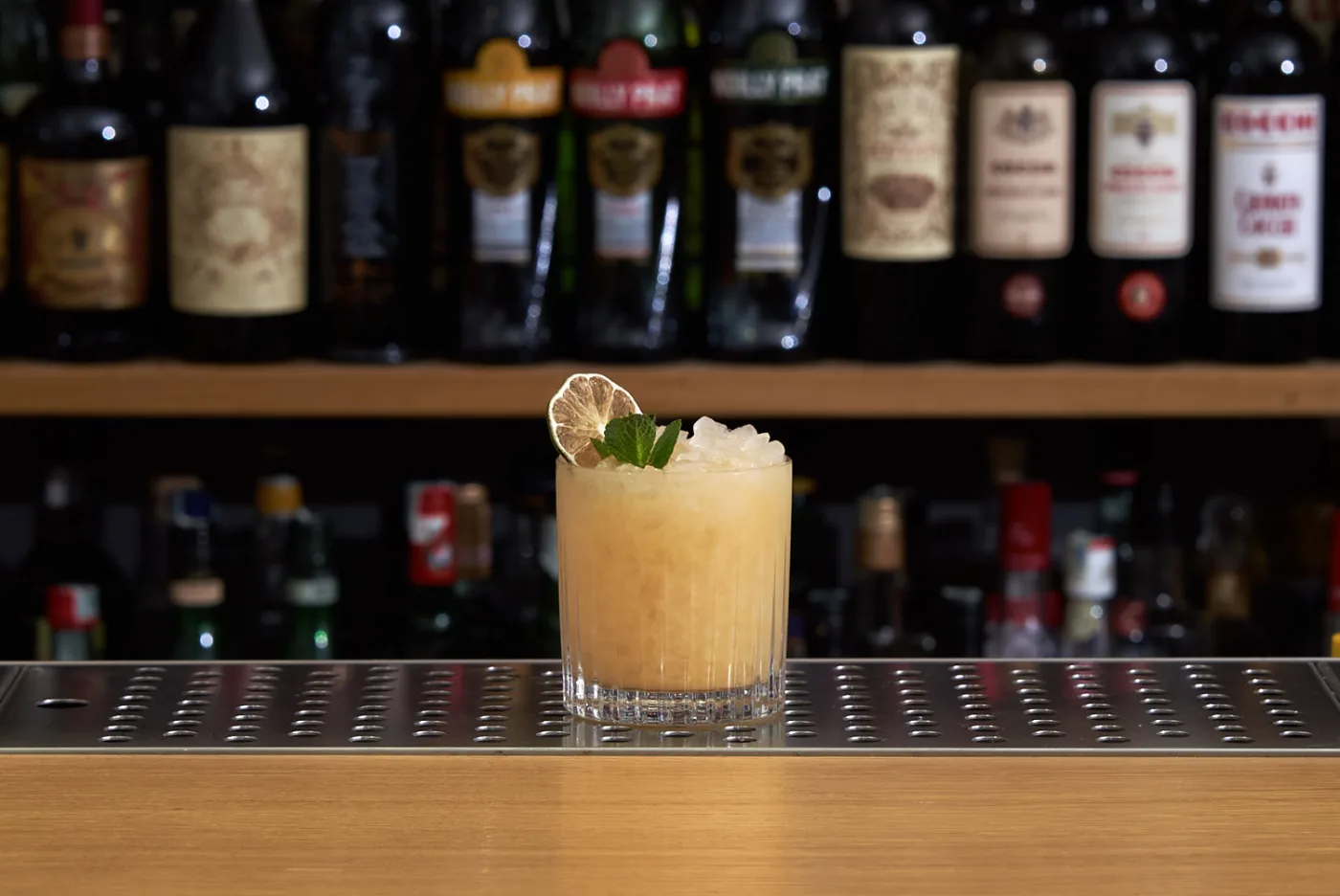 Mai Tai in tumbler basso con ghiaccio tritato, ruota di lime disidratato e ciuffo di menta