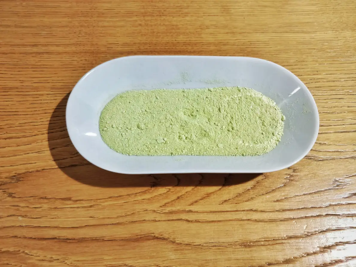 Polvere verde di sale di sedano in un piattino bianco