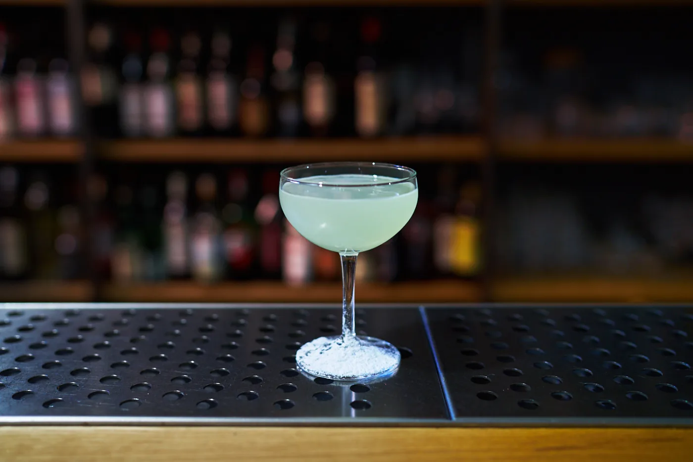 Southside verde pallido in coppetta su banco bar con bottiglie sfocate sullo sfondo