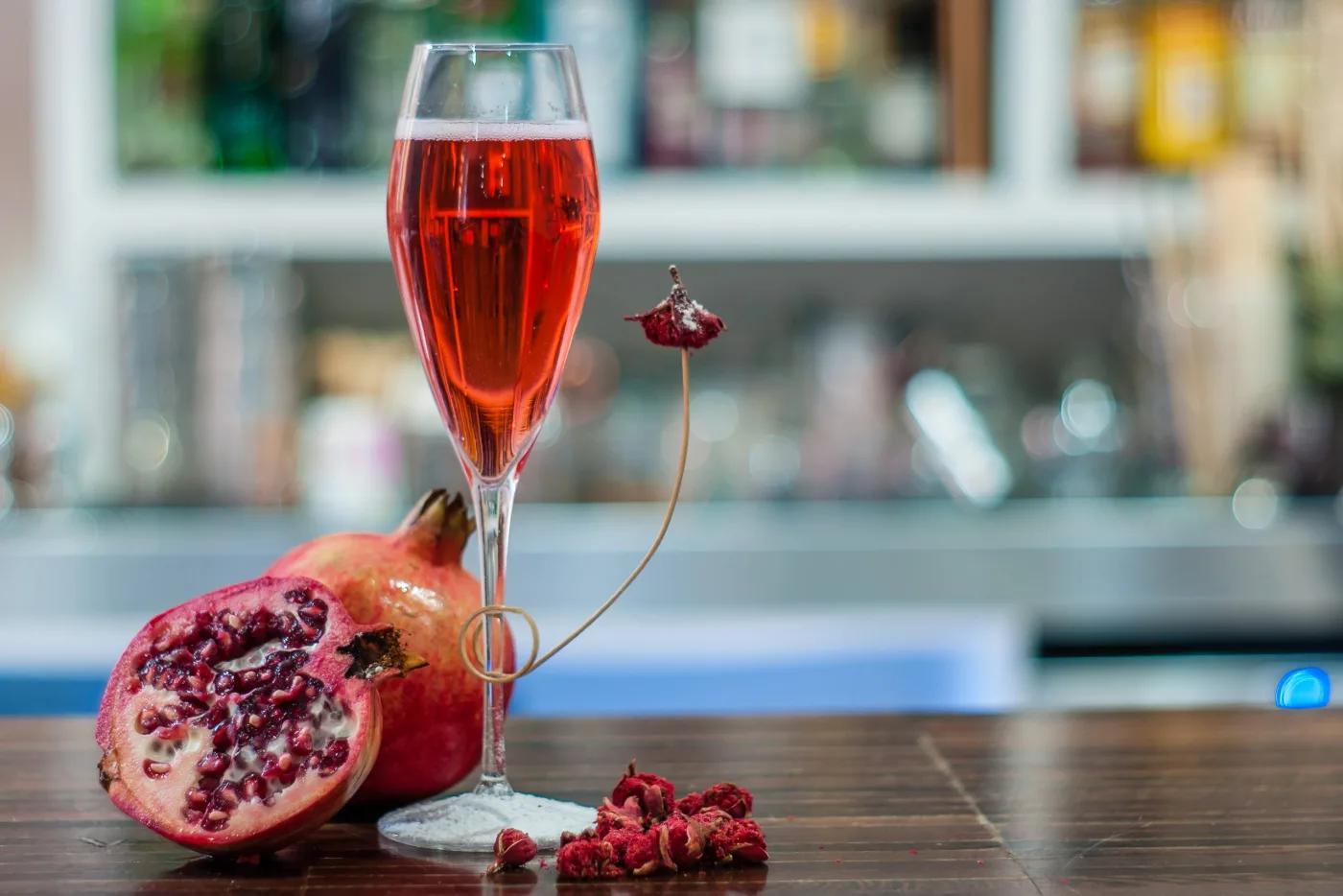 Tintoretto: cocktail con succo di melagrana e prosecco servito in flûte, decorato con un fiore di melagrana essiccato, con melagrane fresche accanto