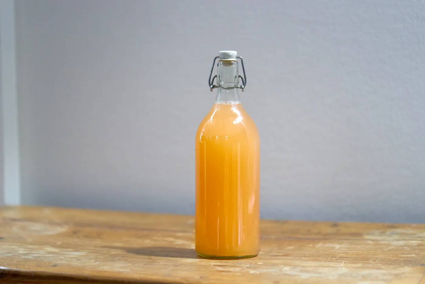 Bottiglia di vino di pesche fermentate home made accanto a delle pesche