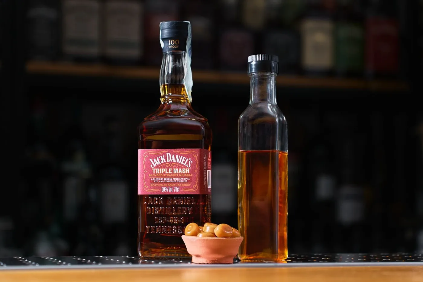 Bottiglia di Jack Daniel's Triple Mash accanto a una bottiglietta di whiskey aromatizzato al toffee e a una ciotolina di caramelle mou