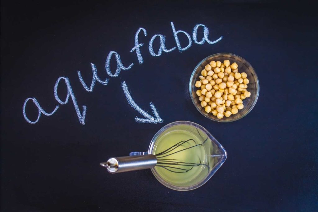 un bicchiere di aquafaba, dei ceci e la scritta aquafaba