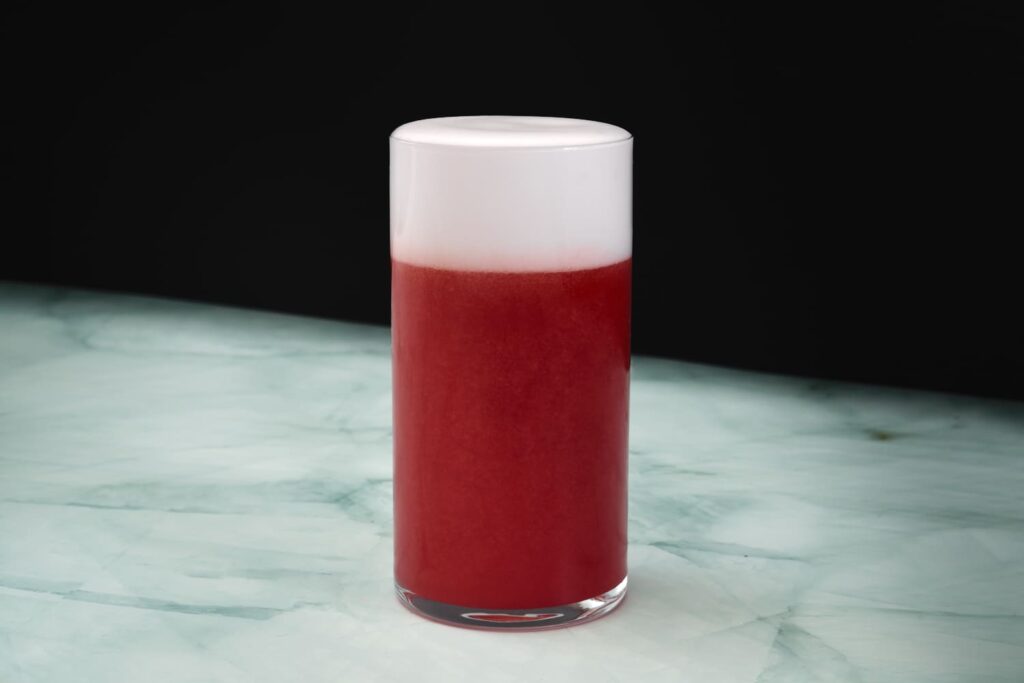 Un drink a base pomodoro e succo di fragola appoggiato su un banco in marmo