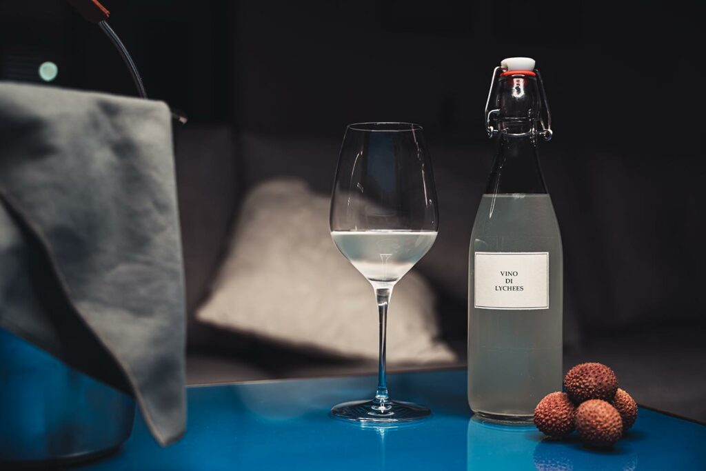 Una bottiglie e bicchiere di un vino rustico fermentato con fermentazione spontanea di Lychees