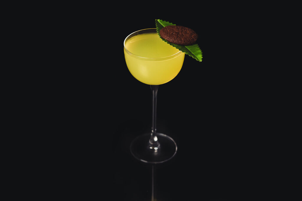 Rio il cocktail a base cachaca zenzero e miele decorato con una foglia di limone e un biscotto