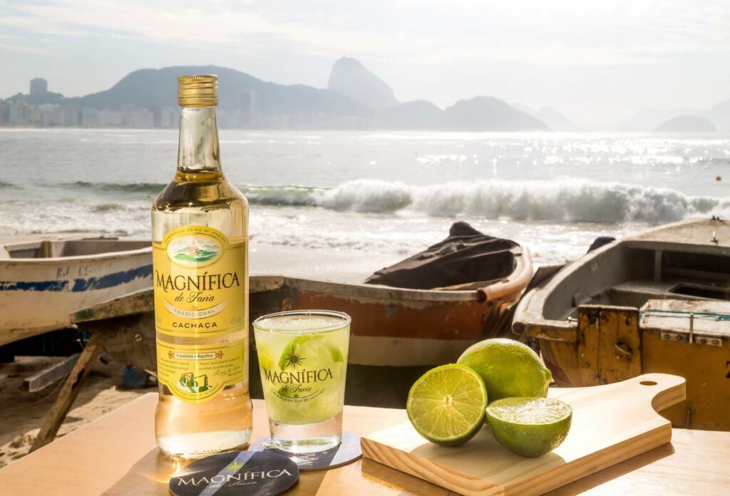 Una bottiglia di Cachaça Magnifica di fianco ad una Caipirinha
