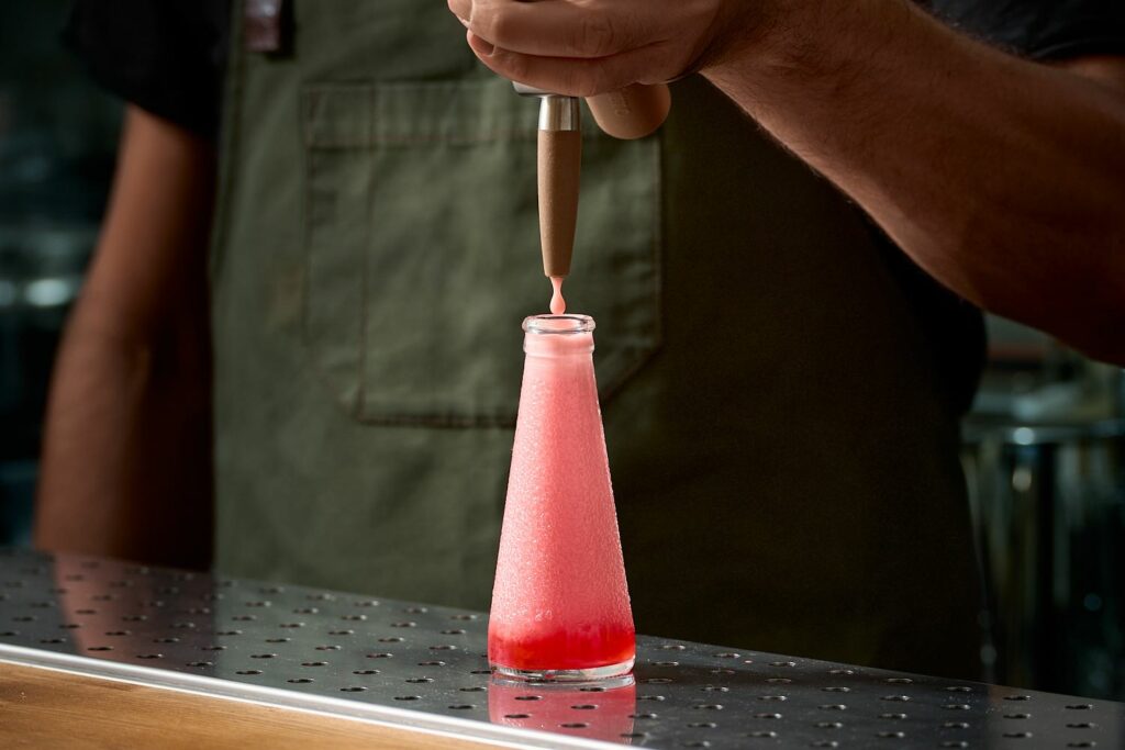 Una Bottiglietta di Campari Soda con all'interno il Cocktail Soldatino Nitro su un banco bar