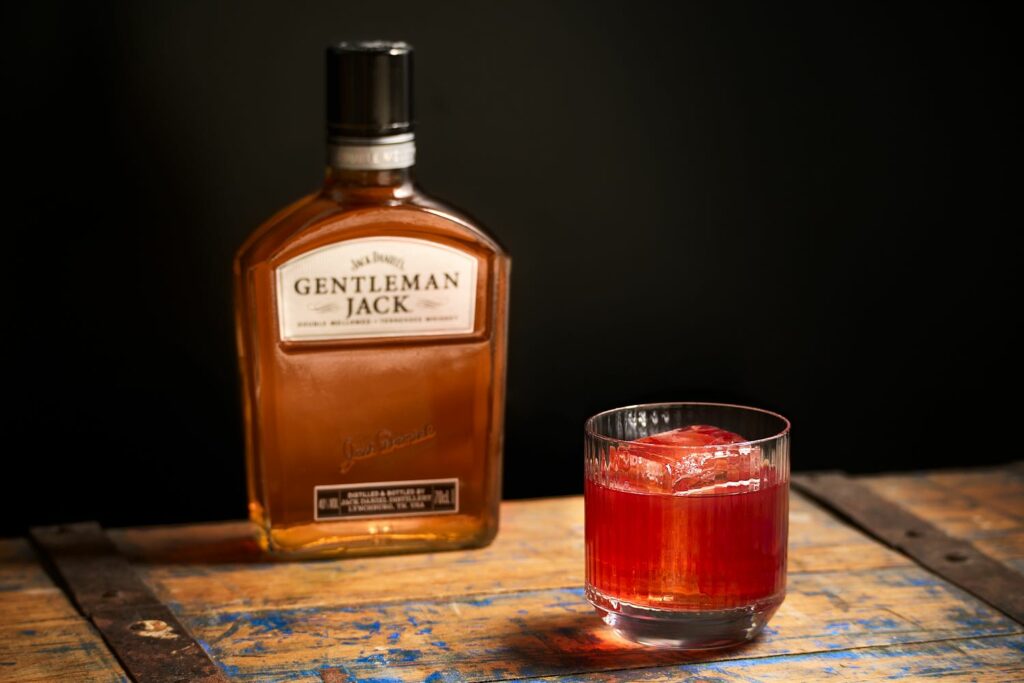 Un bicchiere di Boulevardier al Fresco cocktail con una bottiglia di Whiskey Gentleman Jack