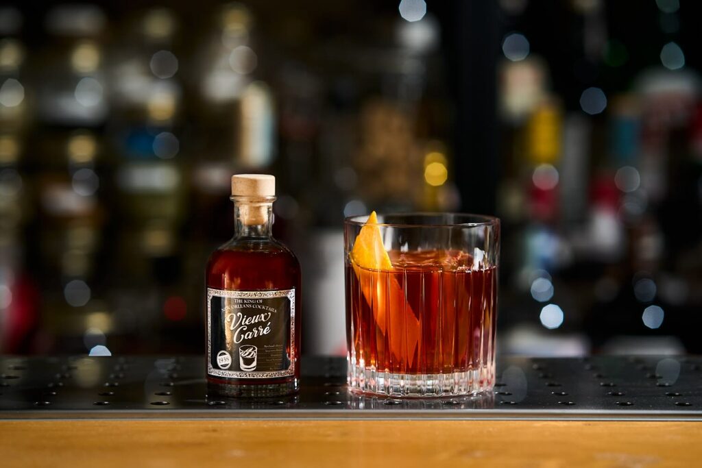 Vieux Carrè invecchiato in tumbler basso con accanto una bottiglietta del drink stesso con etichetta personalizzata.