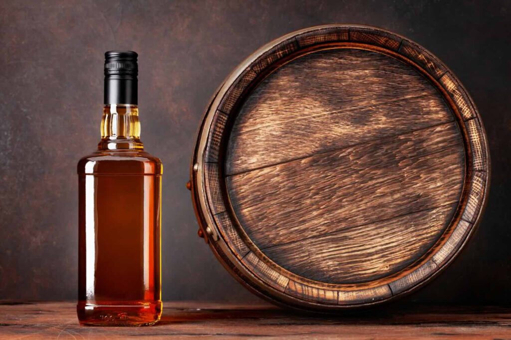 una botte con a fianco una bottiglia di cocktail invecchiato in botte