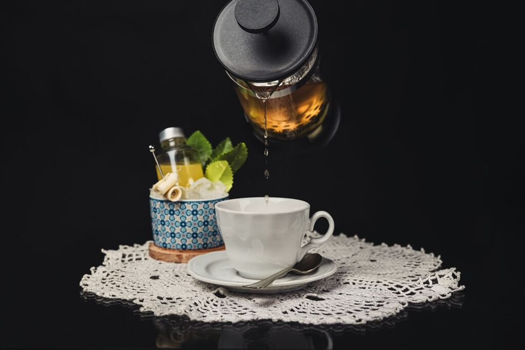 cocktail il guaritore servito in una tazza in ceramica direttamente da una french press. Accanto alla tazza una ciotola che contiene la bottiglietta dello shrub immersa in ghiaccio.