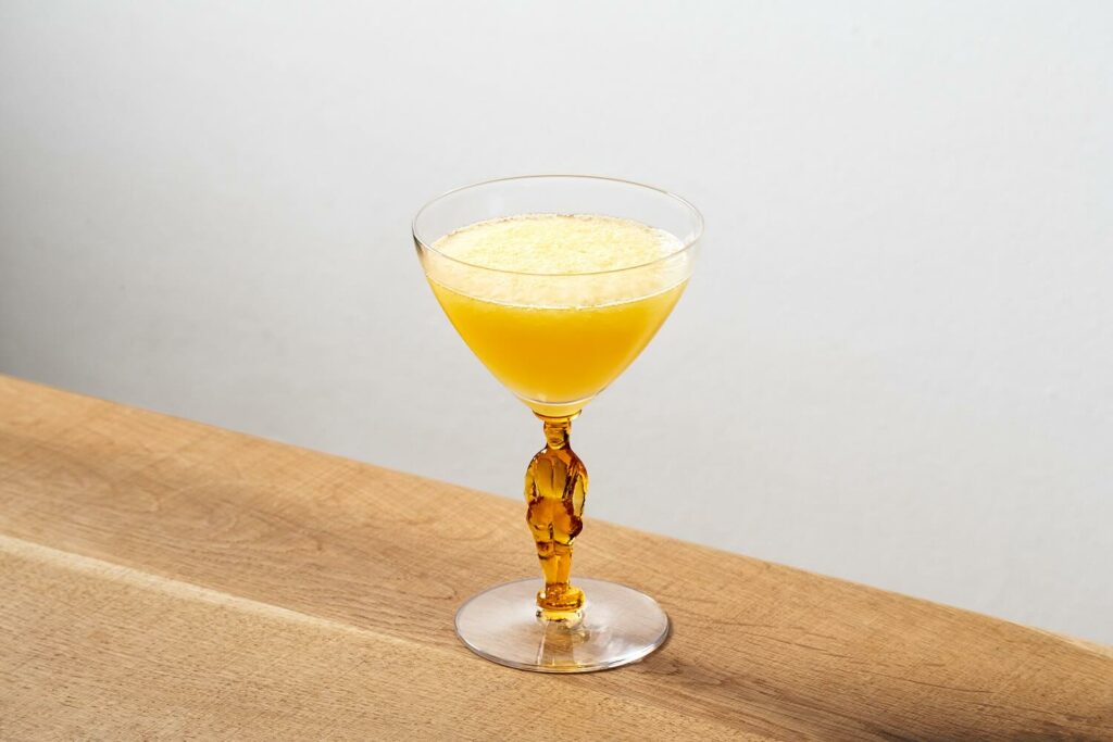 su un tavolo in legno il cocktail Derby Daiquiri composto da rum Portoricano, succhi freschi di arancia e lime, sciroppo di zucchero. Il cocktail è servito nella iconica coppetta prodotta negli anni '50 dalla Morgantown Glass Company