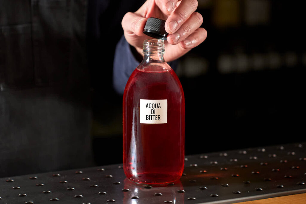 Su un banco bar sun bottiglia contente una preparazione home made chiamata acqua di bitter. La preparazione viene utilizzata nel cocktail