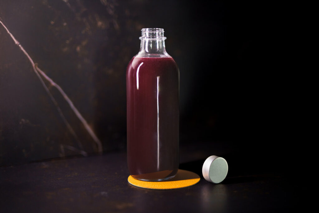 su un piano in marmo una bottiglia che contiene il premix: Black Cherry Mix: una preparazione home made fatta con purea di ciliegie nere e fiori di sambuco