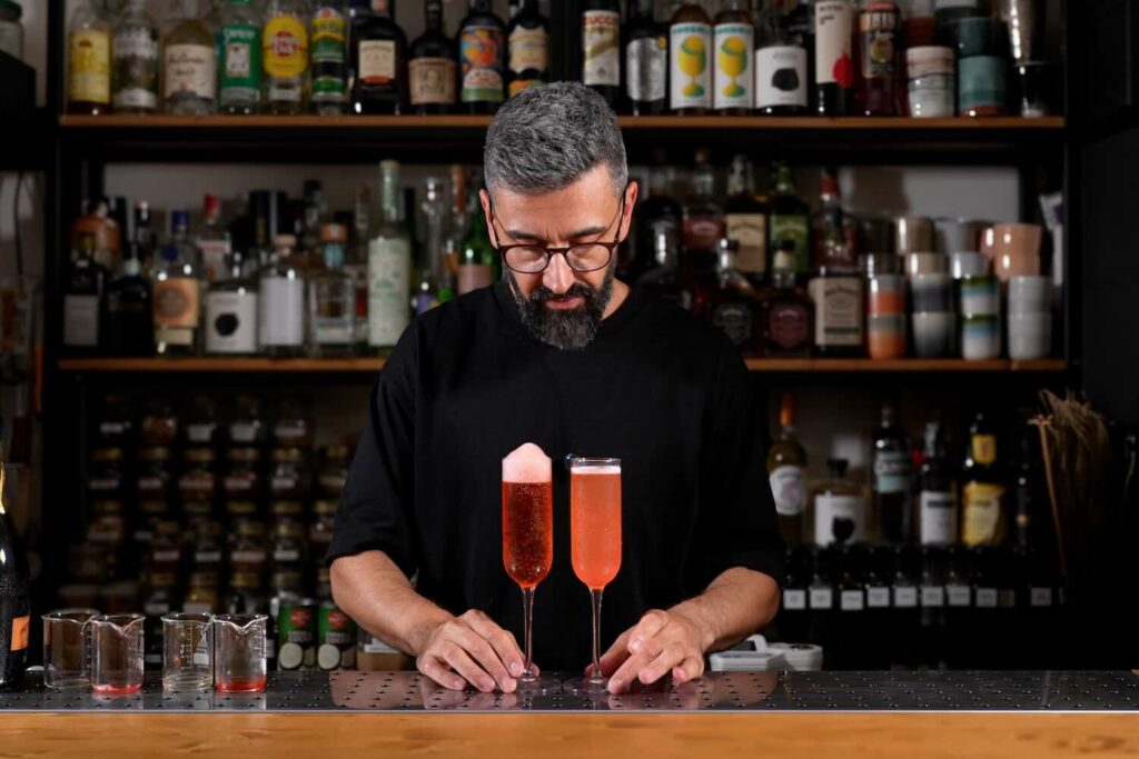 Un bartender che mostra due versioni del Rossini, una con succo chiarificato, decorato con un'aria di fragole e l'altro classico con succo di fragole e prosecco