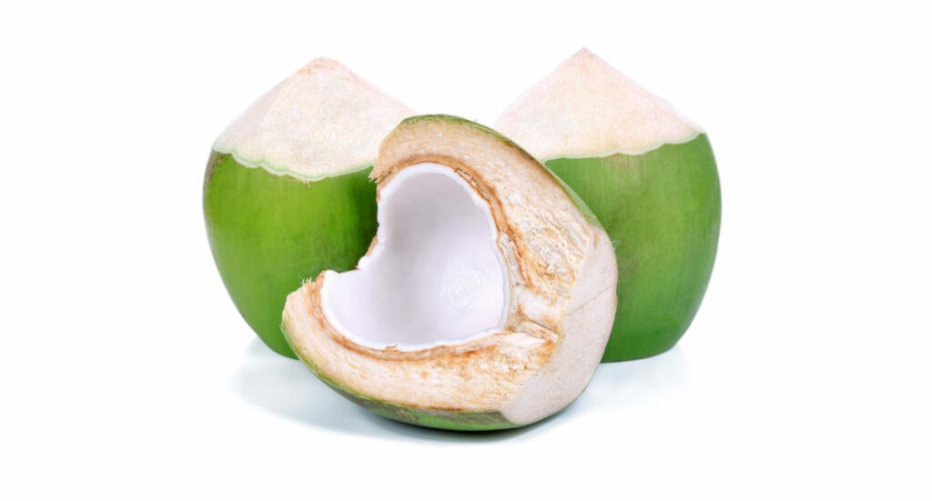 3 noci di cocco verde. 2 sullo sfondo e una aperta a metà in primo piano